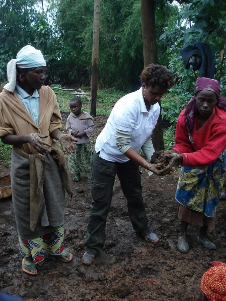 Three women working wet mud with their hands among tall trees