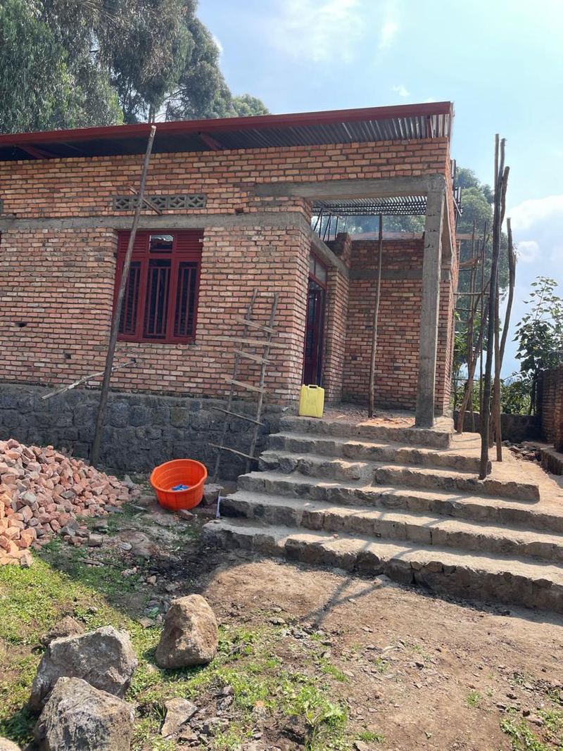 A new brick building with red window frames and stone steps leading up to it