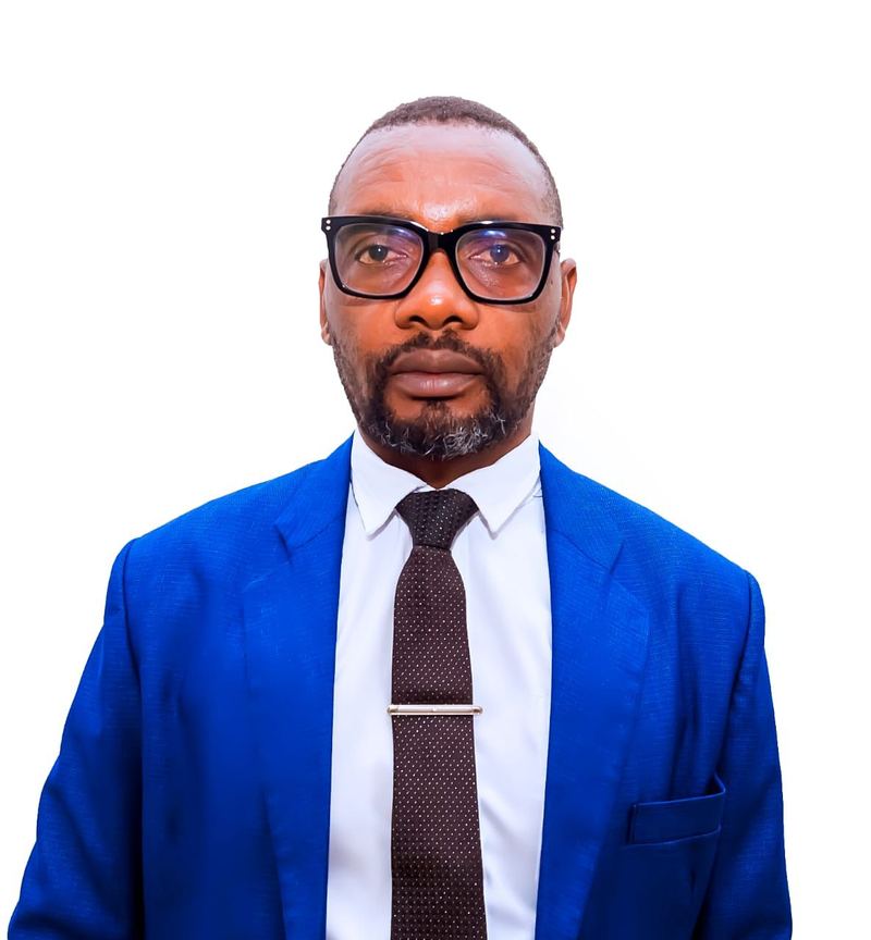 Abiatar Niyitegeka in glasses, a bright blue suit and a dark tie with a tie clip, against a white background