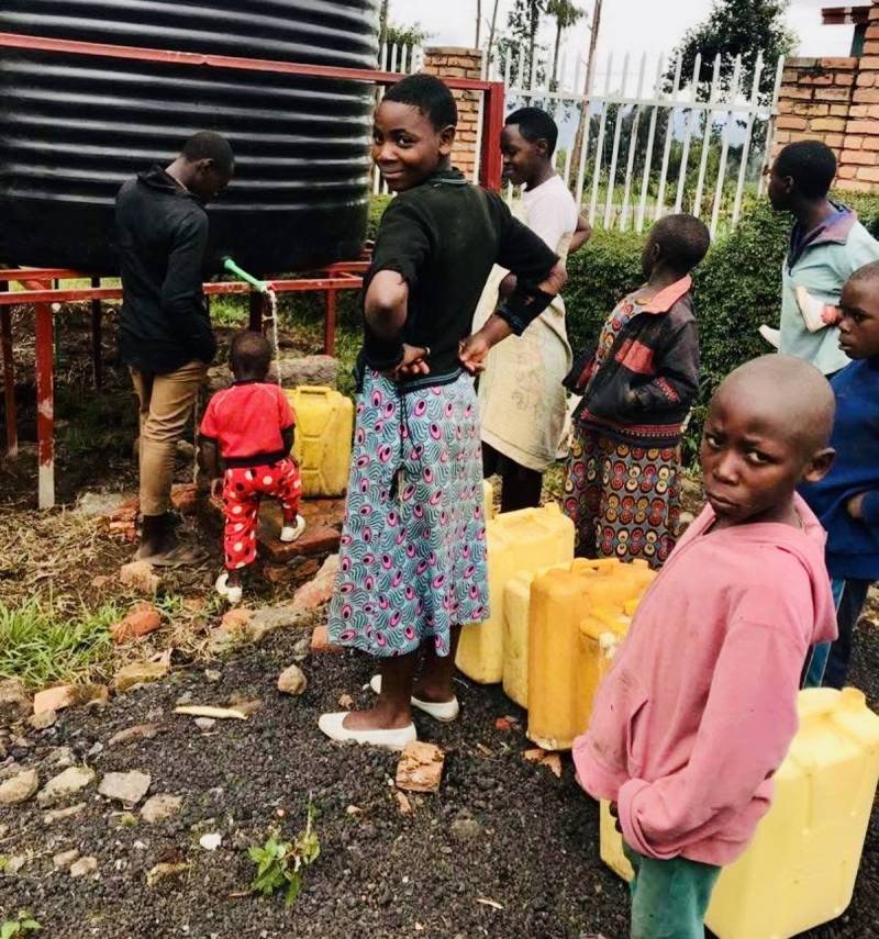 Families and children filling yellow jerrycans at the school’s water tank